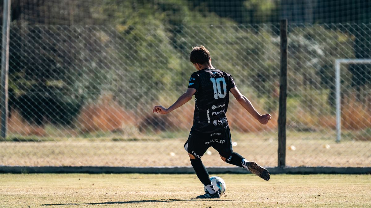 Young soccer player in black jersey with number 10 kicking a ball during a game on a sunny outdoor field. Young soccer player in black jersey with number 10 kicking a ball during a game on a sunny outdoor field.