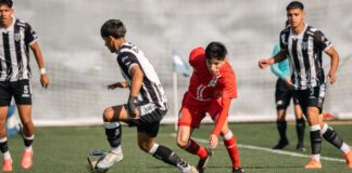 Youth soccer players in dynamic action during a competitive match on a bright day.