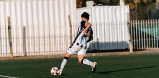 Back view of a young soccer player in motion during a game on a sunny day.