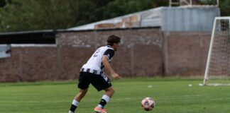 A male soccer player in action on a grassy field during a day match.
