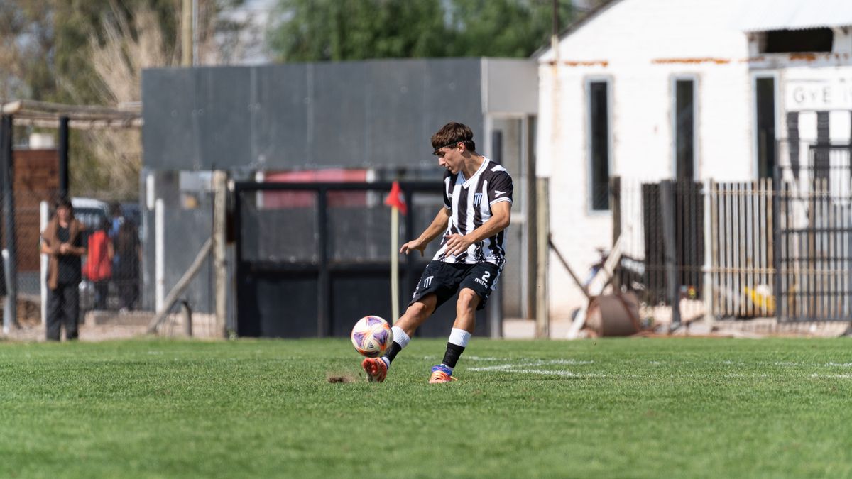 Dynamic action shot of a young male soccer player kicking a ball during a daytime match on an outdoor field. Dynamic action shot of a young male soccer player kicking a ball during a daytime match on an outdoor field.