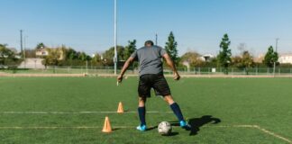 A soccer player practicing drills on a sunny day on an outdoor field.