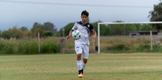 Teenager playing soccer on a grassy outdoor field, showcasing sportsmanship and athleticism.