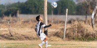 A young soccer player in action performing a header on a grassy outdoor field.