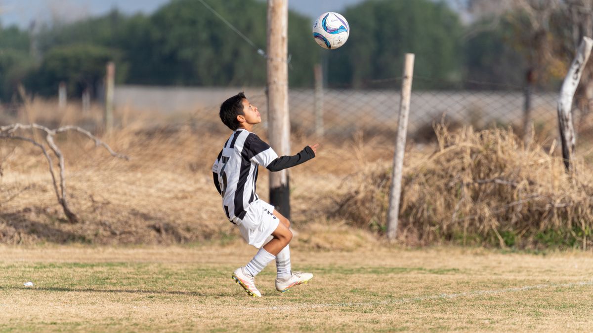 A young soccer player in action performing a header on a grassy outdoor field. A young soccer player in action performing a header on a grassy outdoor field.