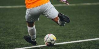Dynamic shot of a soccer player kicking the ball during a game on a grass field.