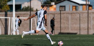 Dynamic shot of a young soccer player kicking a ball during a match on a sunny day.