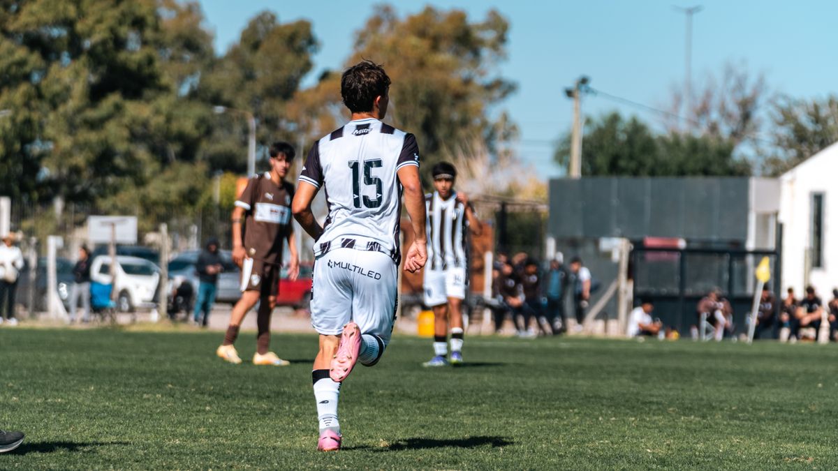 Back view of a soccer player with jersey number 15 running on a green field during a match. Back view of a soccer player with jersey number 15 running on a green field during a match.