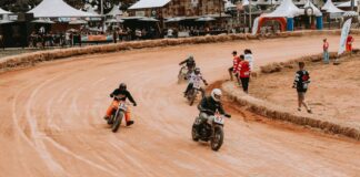 Motorcycles racing on a dirt track with spectators, capturing speed and excitement.