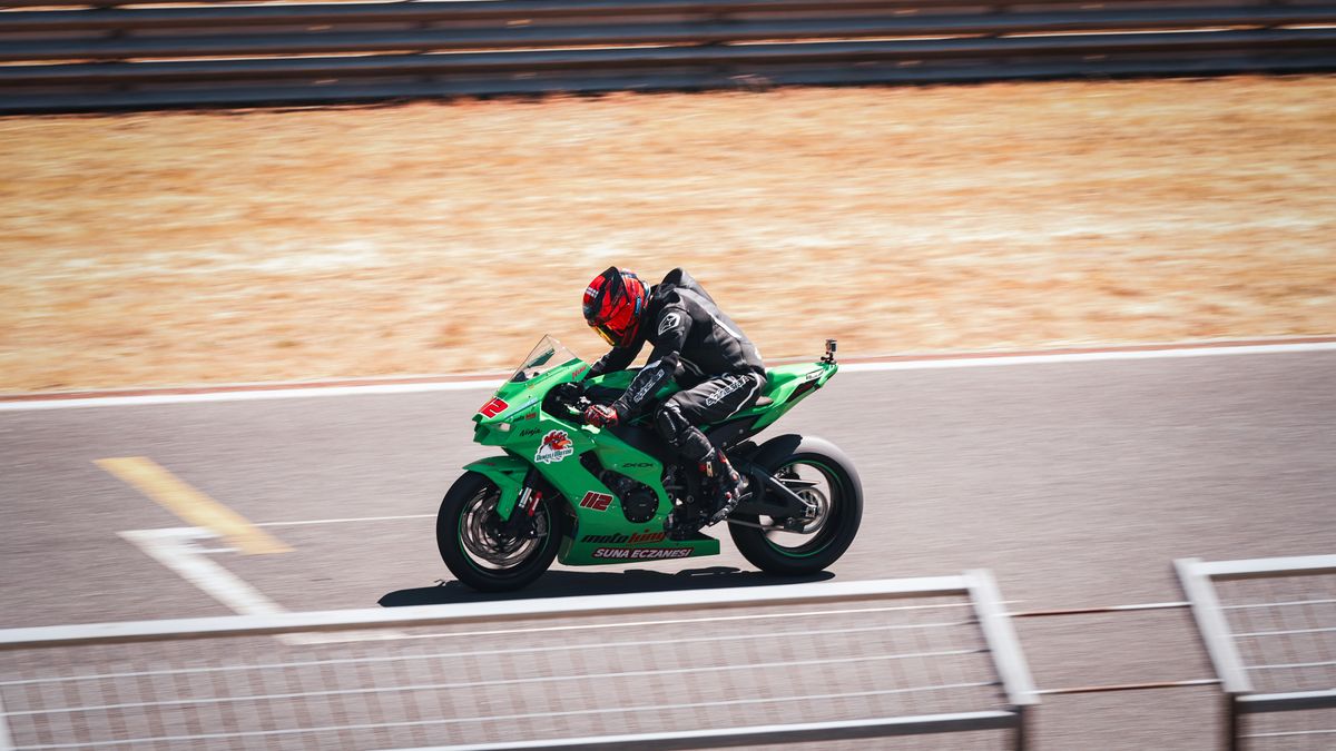 Motorcyclist on a green sportbike speeding on a sunny racetrack, showcasing speed and adrenaline. Motorcyclist on a green sportbike speeding on a sunny racetrack, showcasing speed and adrenaline.