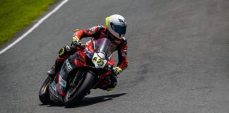 Motorcycle racer leaning into a curve on Batangas racetrack during an intense competition.
