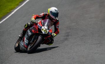Motorcycle racer leaning into a curve on Batangas racetrack during an intense competition.