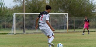 A young soccer player in action on an outdoor field during a daytime match.