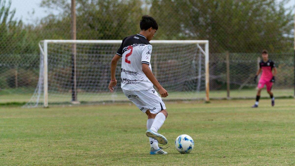 A young soccer player in action on an outdoor field during a daytime match. A young soccer player in action on an outdoor field during a daytime match.