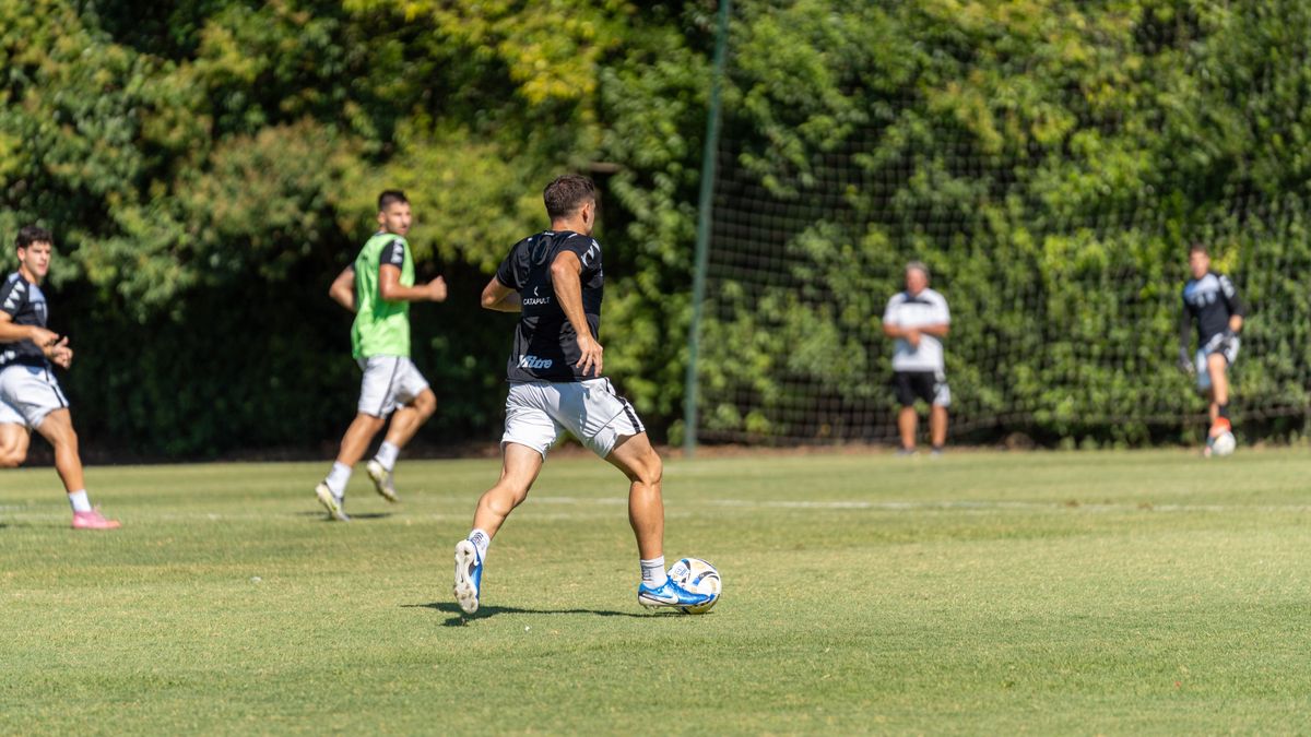 Group of male soccer players practicing on a sunny outdoor field with lush green background. Group of male soccer players practicing on a sunny outdoor field with lush green background.