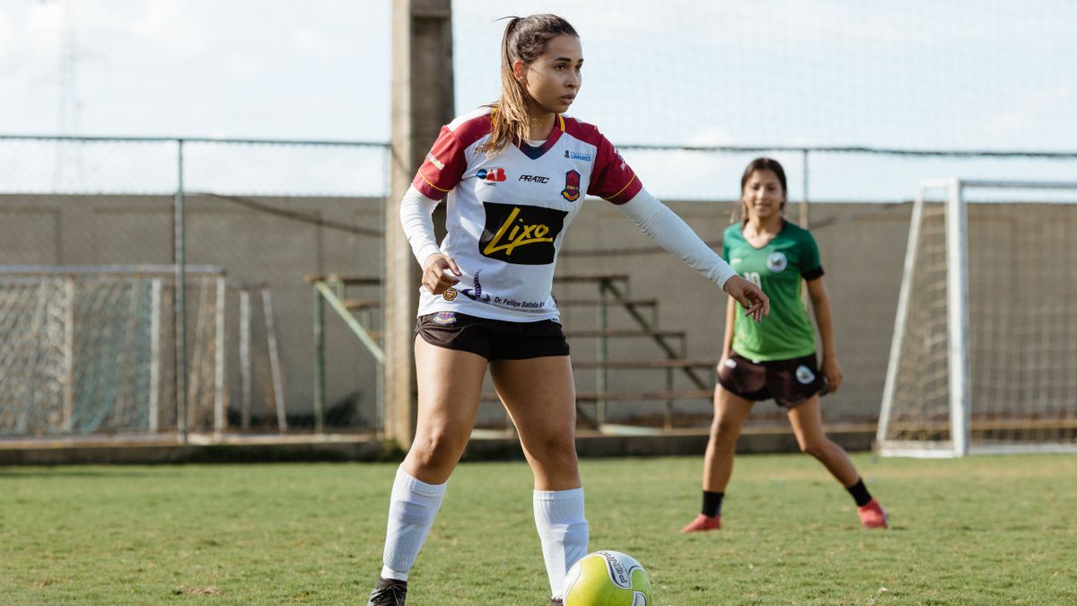 Two teenage girls engaged in a soccer game on an outdoor field, wearing sportswear. Two teenage girls engaged in a soccer game on an outdoor field, wearing sportswear.