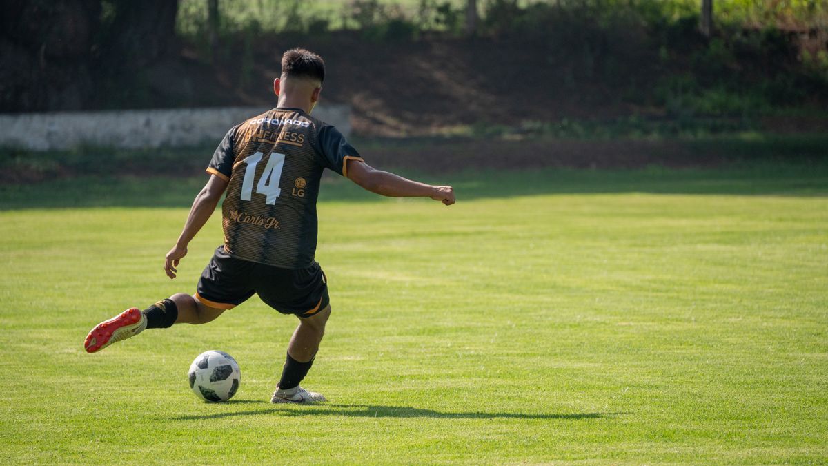 A soccer player prepares to kick the ball on a grassy field during daylight. A soccer player prepares to kick the ball on a grassy field during daylight.