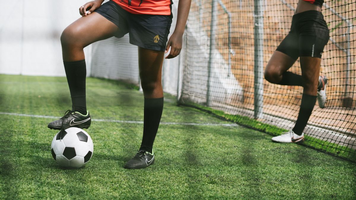 Faceless black female soccer players with ball on sports ground during practicing Faceless black female soccer players with ball on sports ground during practicing