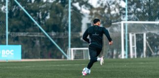 Football player practices dribbling on a professional outdoor field, emphasizing athleticism and skill.