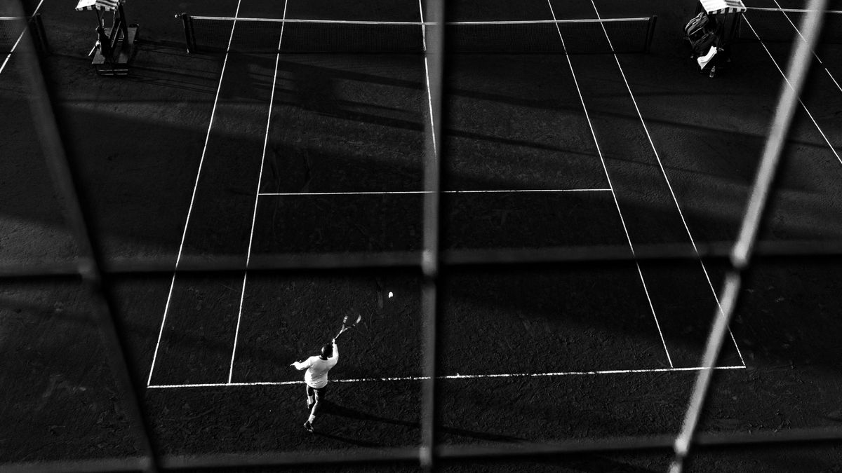 Black and white photo of a tennis match in Buenos Aires, capturing dynamic motion and shadow play. Black and white photo of a tennis match in Buenos Aires, capturing dynamic motion and shadow play.