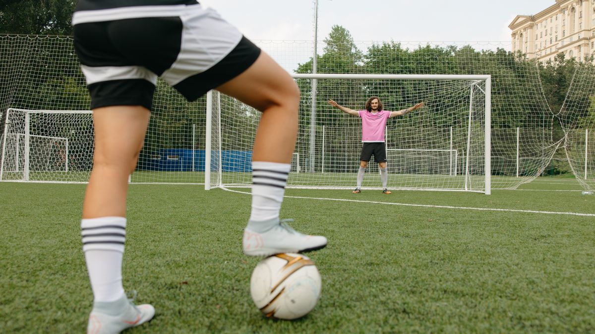Soccer player in action aiming for the goal with a goalkeeper ready to defend. Soccer player in action aiming for the goal with a goalkeeper ready to defend.