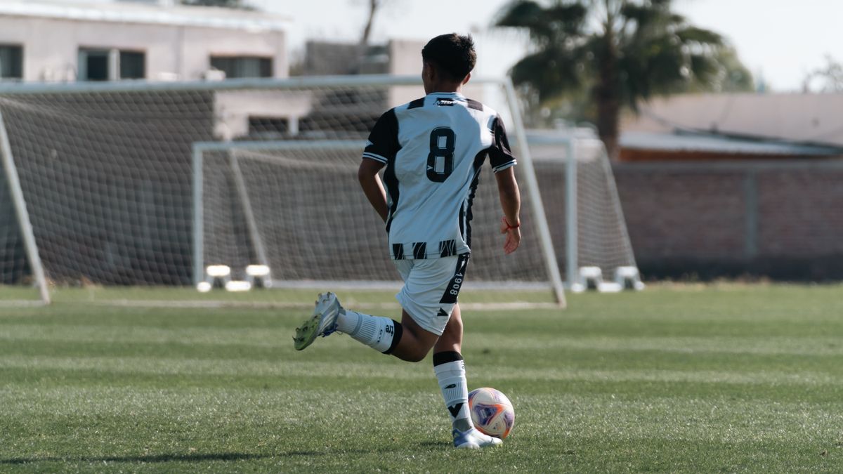 A young soccer player wearing a number 8 jersey runs with the ball on a sunny outdoor field. A young soccer player wearing a number 8 jersey runs with the ball on a sunny outdoor field.