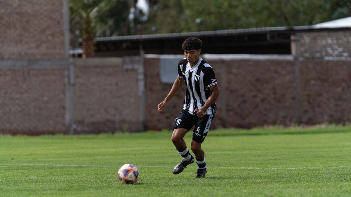 Young male soccer player dribbling on grassy field during a daytime match. Young male soccer player dribbling on grassy field during a daytime match.