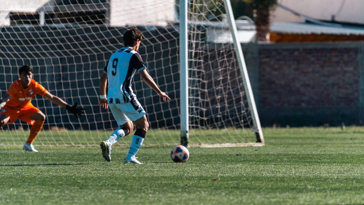 Soccer player in action taking a shot towards goal with goalkeeper ready to defend. Soccer player in action taking a shot towards goal with goalkeeper ready to defend.