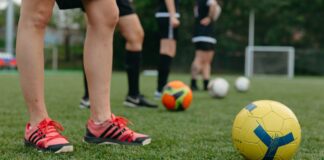 Close-up of soccer players on a grass field with colorful soccer balls, displaying teamwork and sportsmanship.