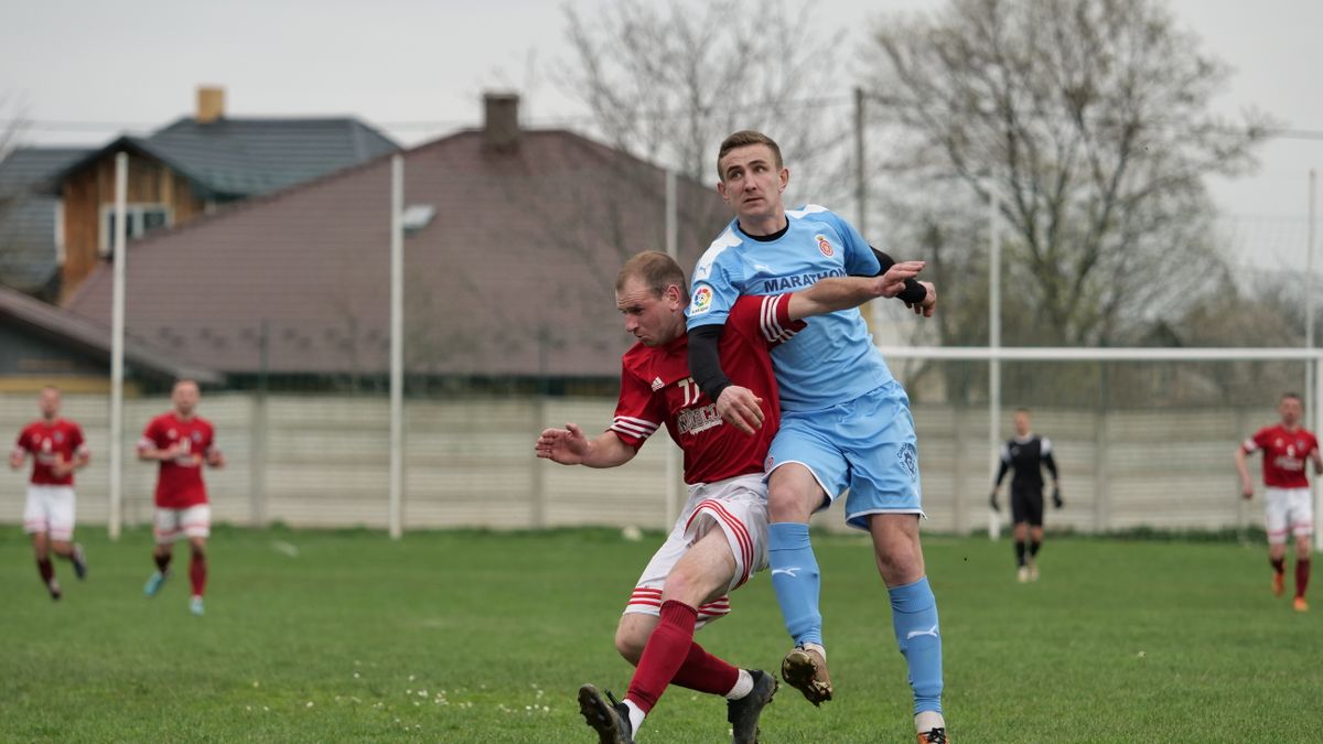 Players fiercely competing in a local football match on an outdoor grassy field. Players fiercely competing in a local football match on an outdoor grassy field.