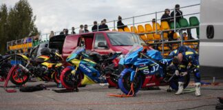 Racers prepping bikes for a motorsport event at an outdoor track.