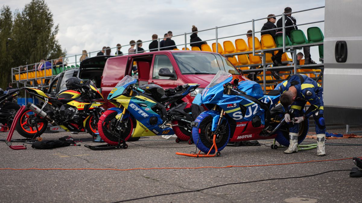 Racers prepping bikes for a motorsport event at an outdoor track. Racers prepping bikes for a motorsport event at an outdoor track.