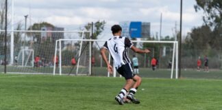 Youth soccer player wearing number 6 in striped jersey, playing outdoors.