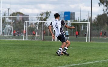 Youth soccer player wearing number 6 in striped jersey, playing outdoors.