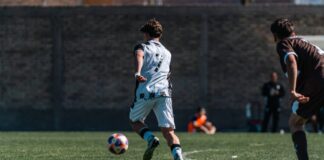 A dynamic scene of two players in a competitive soccer match on a sunny field.