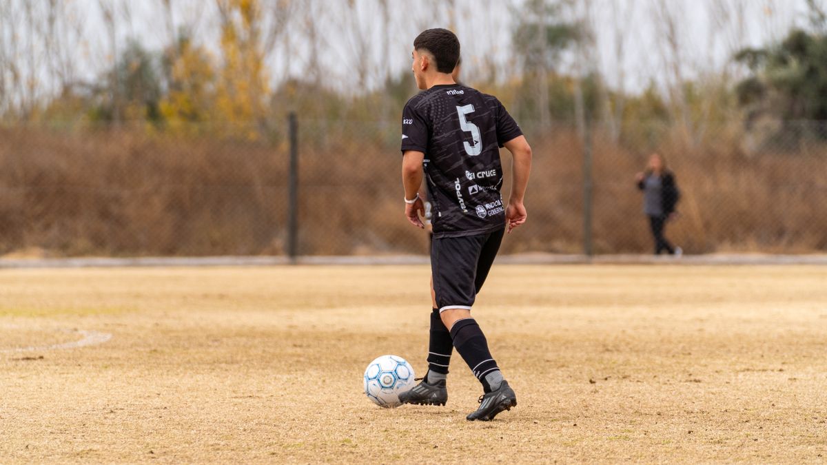 A soccer player in black jersey prepares to pass on an outdoor field. A soccer player in black jersey prepares to pass on an outdoor field.