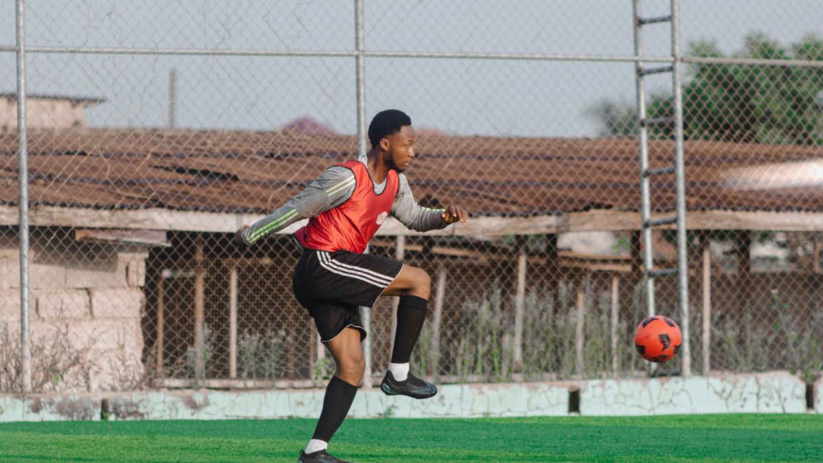Young male soccer player practicing on outdoor field with red jersey. Young male soccer player practicing on outdoor field with red jersey.