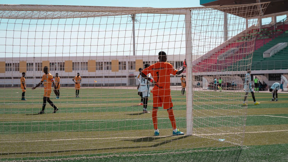 Soccer players in action during a competitive match, focusing on the goalkeeper's stance. Soccer players in action during a competitive match, focusing on the goalkeeper's stance.