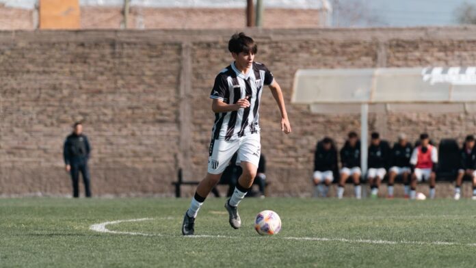Teenage soccer player dribbling on a sunny day during a match with teammates in the background. Teenage soccer player dribbling on a sunny day during a match with teammates in the background.