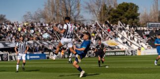 Dynamic scene of players in action during a soccer match at a crowded stadium.