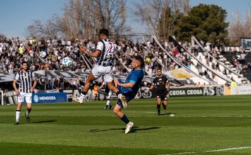 Dynamic scene of players in action during a soccer match at a crowded stadium.
