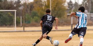 Youth soccer players in action during a competitive outdoor game on a grass field.