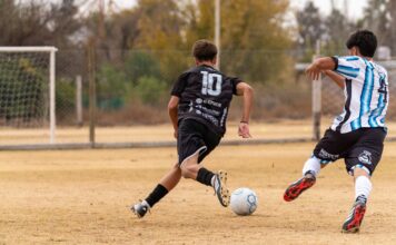 Youth soccer players in action during a competitive outdoor game on a grass field.
