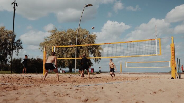 Group of men playing beach volleyball on a sunny day in Jönköping, Sweden.