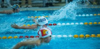 Energetic swimmers competing in a butterfly stroke race at an indoor swimming pool.