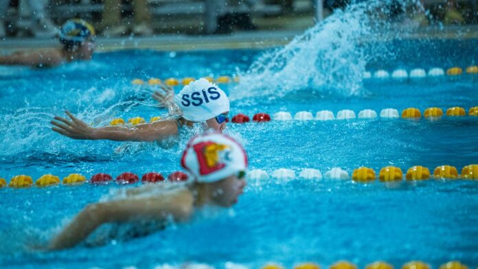 Energetic swimmers competing in a butterfly stroke race at an indoor swimming pool. Energetic swimmers competing in a butterfly stroke race at an indoor swimming pool.