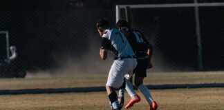 Two soccer players competing on a field during a daytime match.