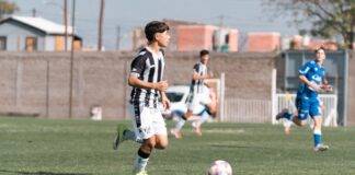 Teenage soccer players in action during a match on an outdoor field under daylight.
