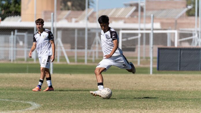 Two young soccer players in action on the field during daytime. Two young soccer players in action on the field during daytime.