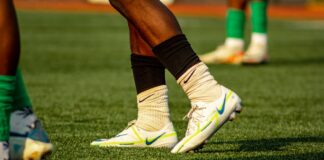 Soccer players training on a grass field in bright cleats and socks.